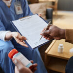Black Man Signing Medical Form on Clipboard